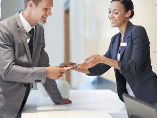 una recepcionista femenina ayudando a un cliente masculino