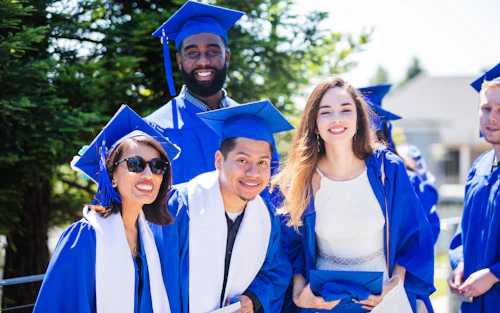 four students at graduation wearing caps and gowns