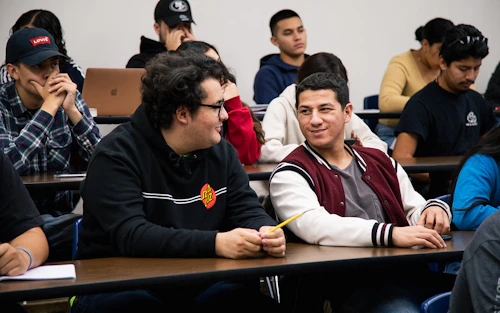 two smiling male students sitting in class
