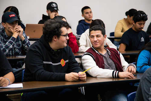dos estudiantes varones sonrientes sentados en clase