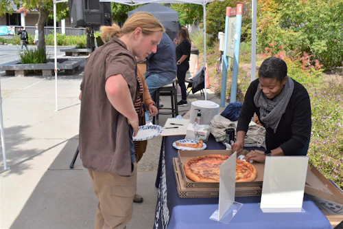 Student Assistant Serving Pizza at OSE Open House