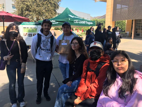 Grupo de estudiantes afuera con el toldo LSAMP en el fondo