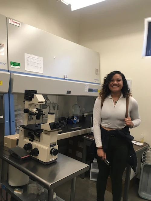 Estudiante se encuentra en el laboratorio de ciencias con microscopio y estación de flujo