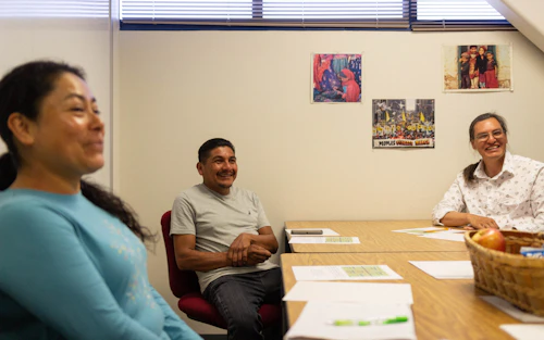 3 students smile while sitting at a table