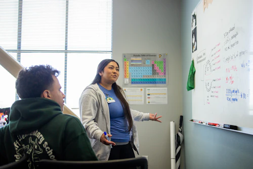 una tutora de química explica un concepto a un estudiante.