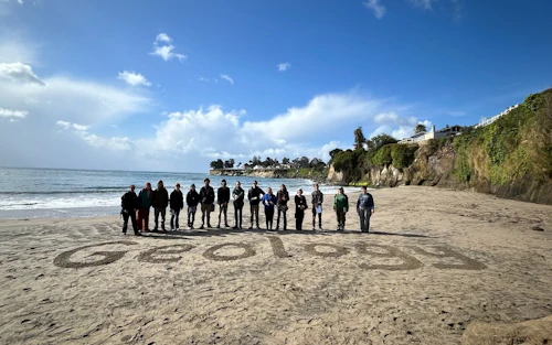 estudiantes en la playa frente a la palabra geología escrita en la arena