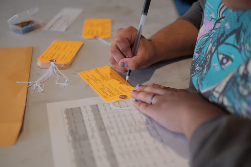 Close up a a person filling out an orange tab