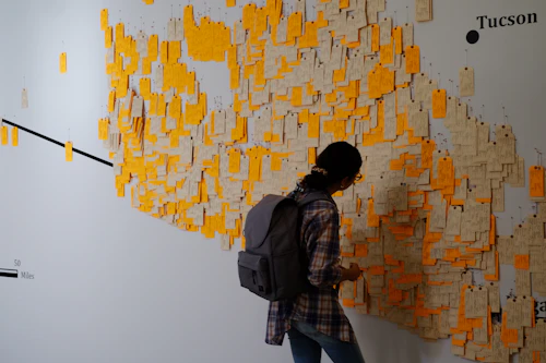 A person stands in front of a wall map with thousands of tags