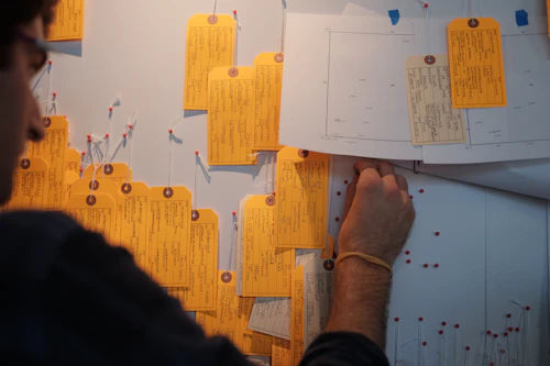 A person pins tags onto the wall
