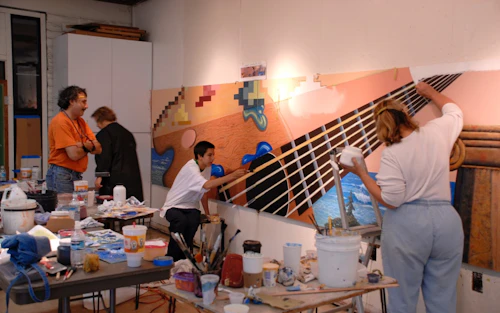 Estudiantes pintando un mural de una guitarra