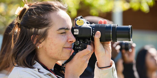 A woman squints into a camera while taking a photo.
