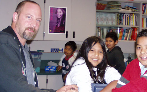 Un profesor varón participa en un proyecto de aula con varios estudiantes latinos.