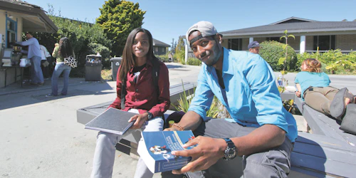 A female and male student sit on a bench in the upper quad on the Cabrillo College campus