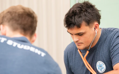 Un estudiante de EMT con un estetoscopio revisa a un paciente.