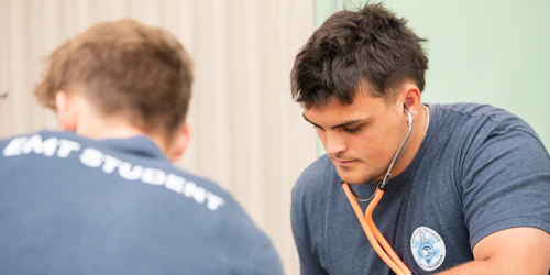 Un estudiante de EMT con un estetoscopio revisa a un paciente.