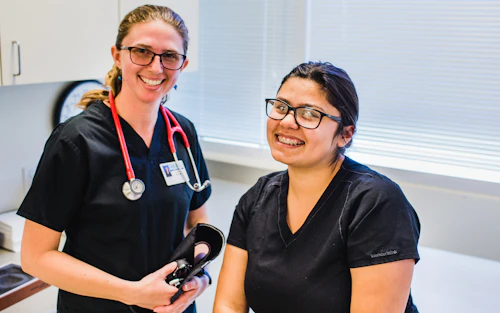 Dos estudiantes de medicina sonríen en un consultorio médico.