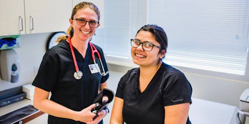 Dos estudiantes de medicina sonríen en un consultorio médico.
