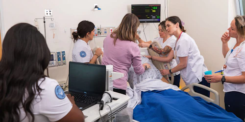 A group of nurses confer around a patient in an hospital