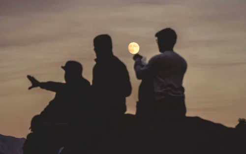 Tres jóvenes observan una luna llena.