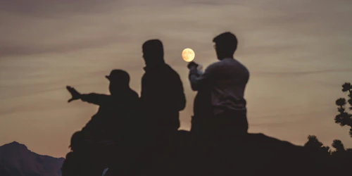Tres jóvenes observan una luna llena.
