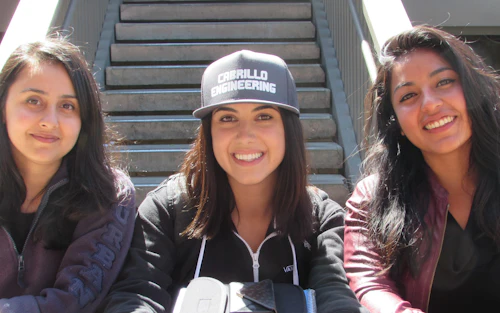 Tres estudiantes de ingeniería sonríen a la cámara.