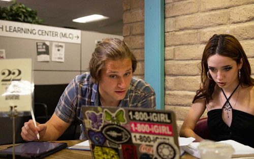 Un tutor de matemáticas instruye a una estudiante en una computadora portátil.