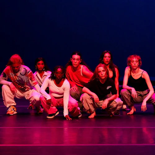 A group of dancers squatting on stage in the middle of a routine