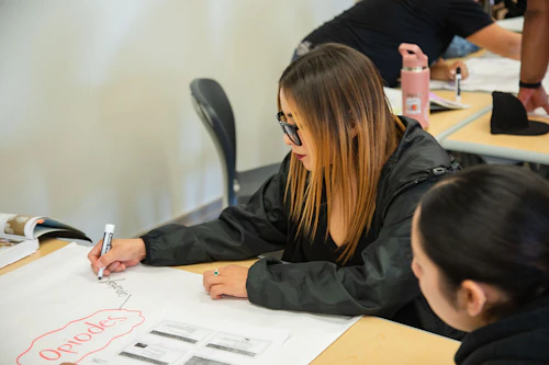 una estudiante de servicios humanos escribiendo en una cartulina