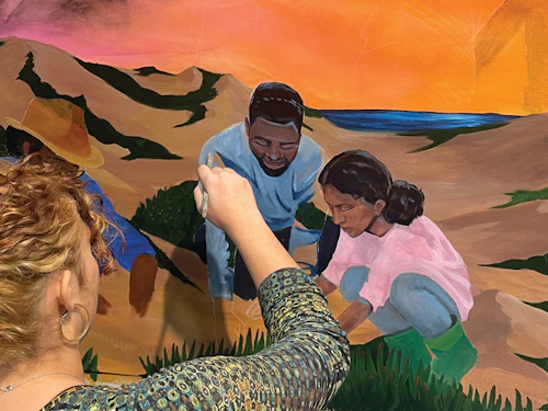 A student paints a section of the African American mural