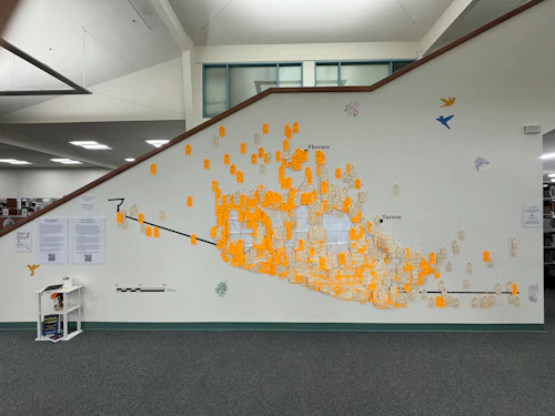 Cabrillo Library wall with yellow and beige tags representing migrants who have died in the Sonoran desert