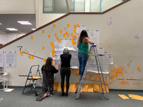 3 people pin tags to the wall