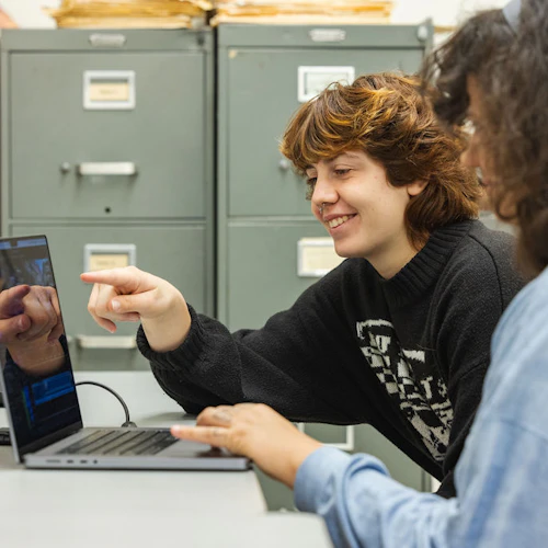 estudiantes sonriendo y mirando una laptop
