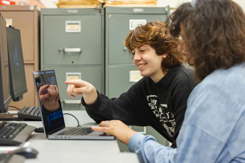 estudiantes sonriendo y mirando una laptop
