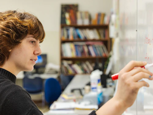 estudiante escribiendo en una pizarra blanca
