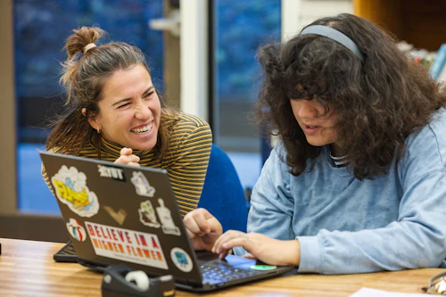 personal con un estudiante en una computadora portátil
