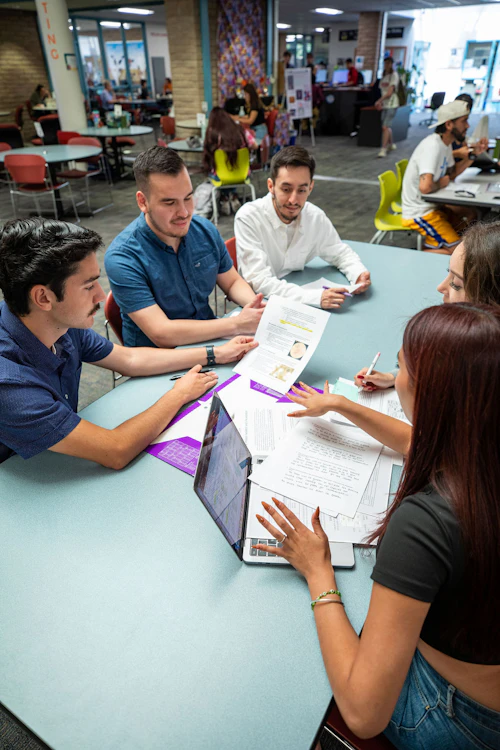 Estudiantes de Cabrillo sentados alrededor de una mesa con una computadora portátil discutiendo trabajo escolar.