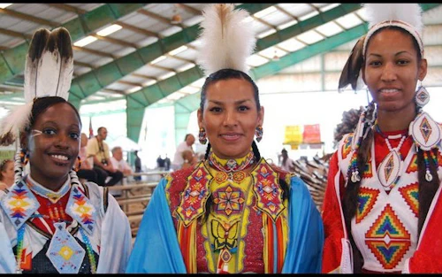 three Black women dressed in traditional indigenous attire