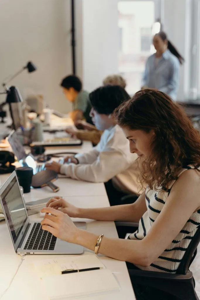 female student sitting at a computer with other students in class