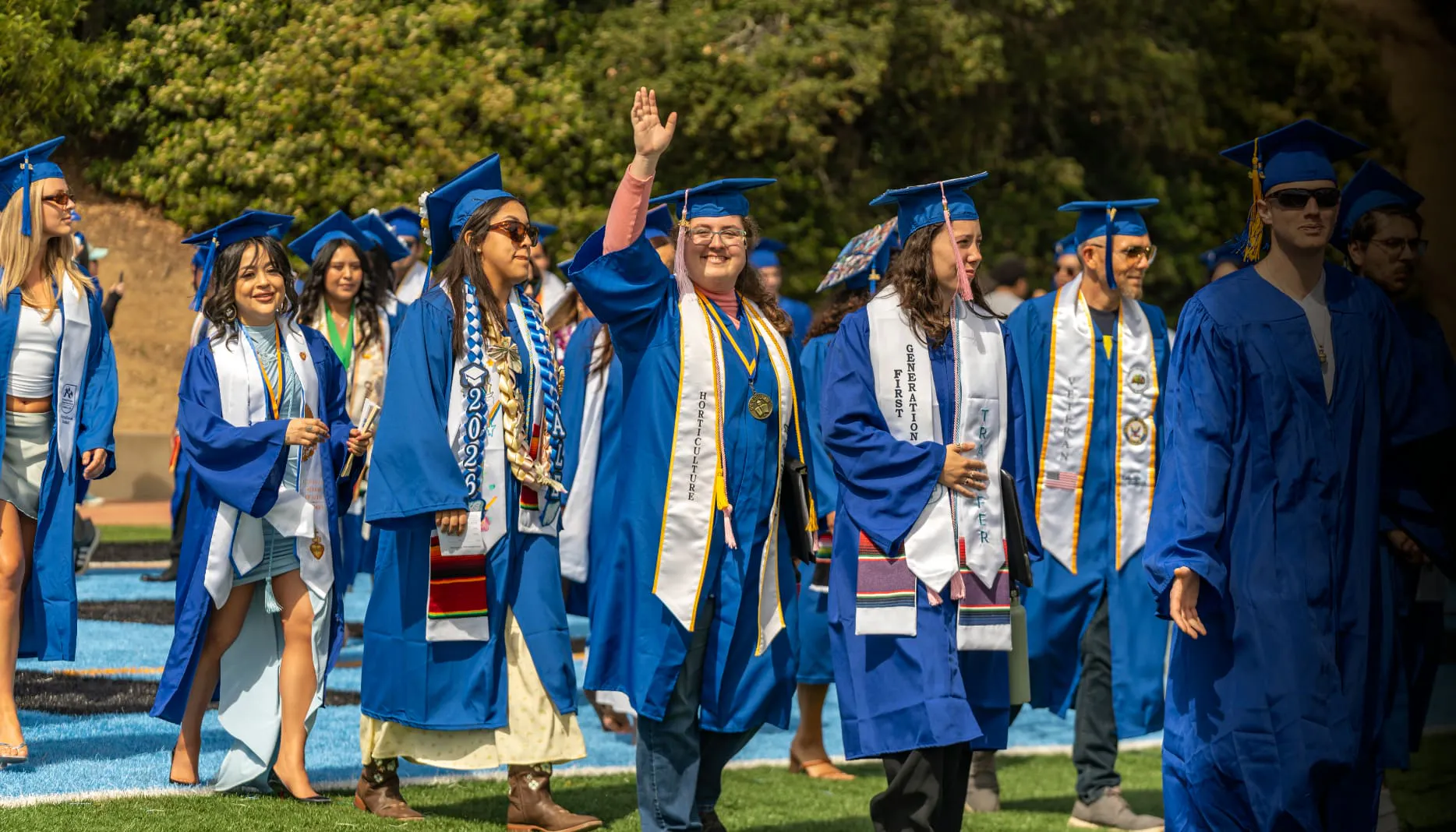 Cabrillo students in blue robes walk across the stage at the 2026 graduation